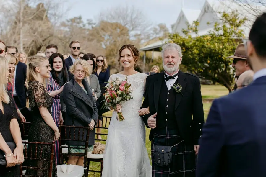 Bride holding her bouquet and walking down the aisle with an older man