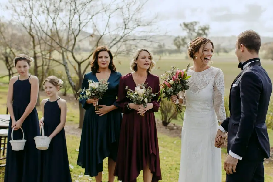 Bride laughing with the groom as bridesmaids and two girls stand beside her