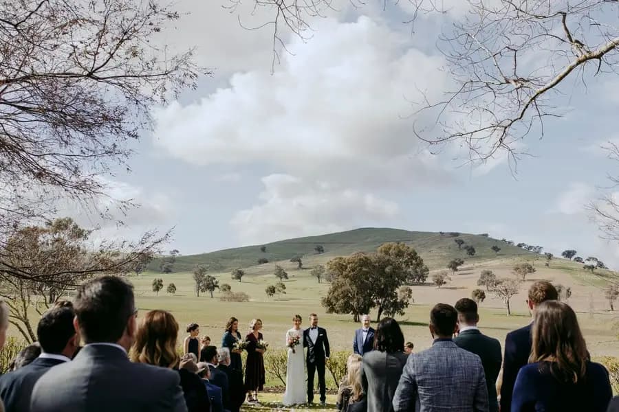 View through standing guests towards the bride and groom at their outdoor ceremony