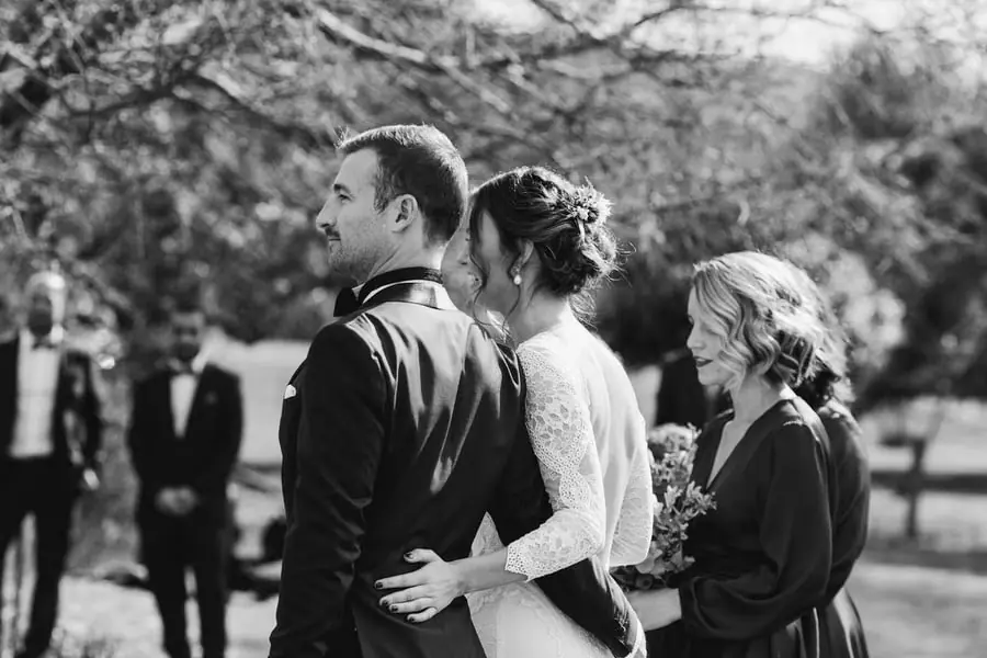 Black-and-white photograph of the bride with her arm around the groom during the ceremony