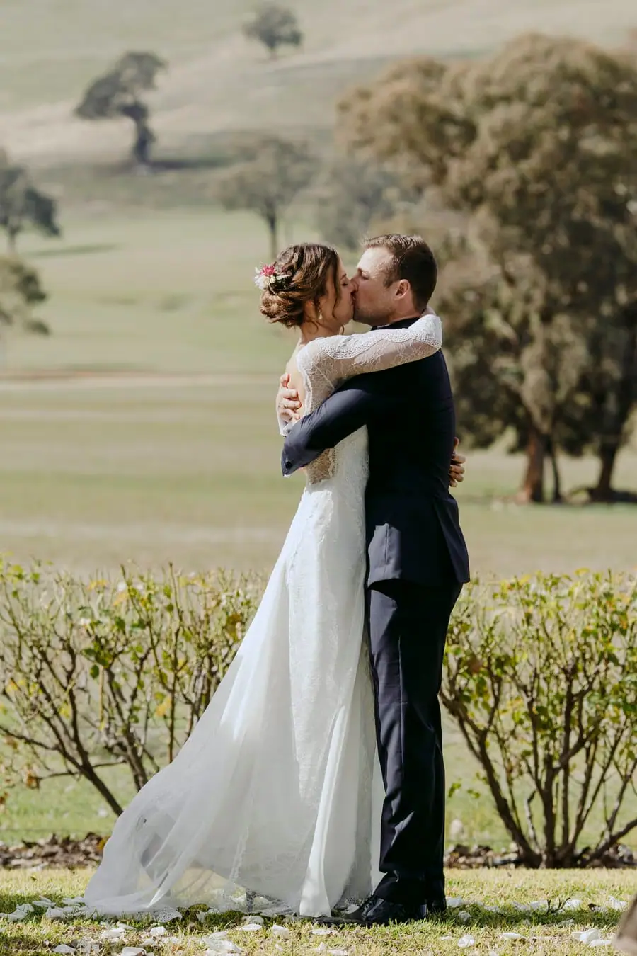 Bride and groom embracing and kissing during the outdoor ceremony