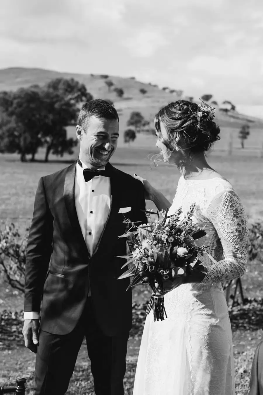 Black-and-white photograph of the bride and groom standing together with her bouquet