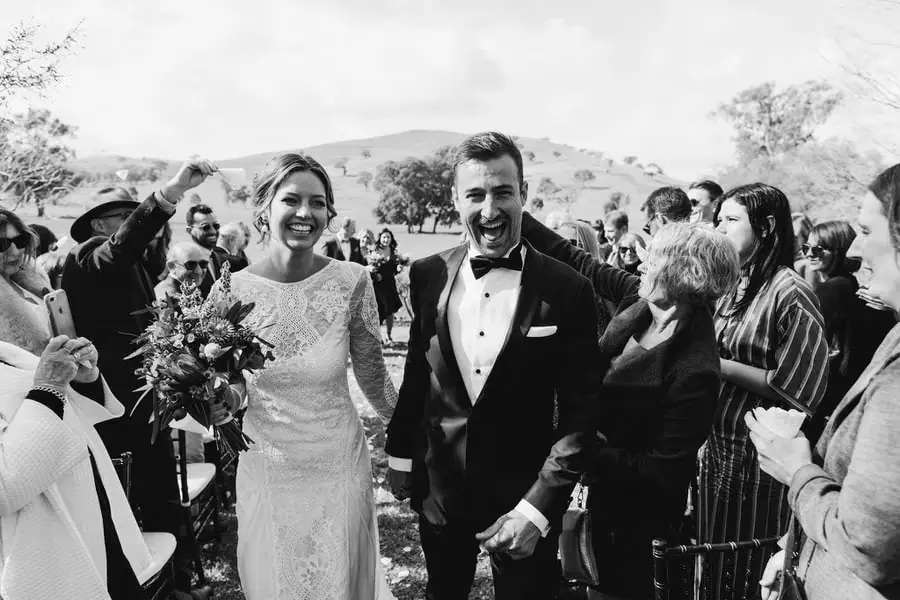 Black-and-white photograph of the smiling couple walking through falling petals