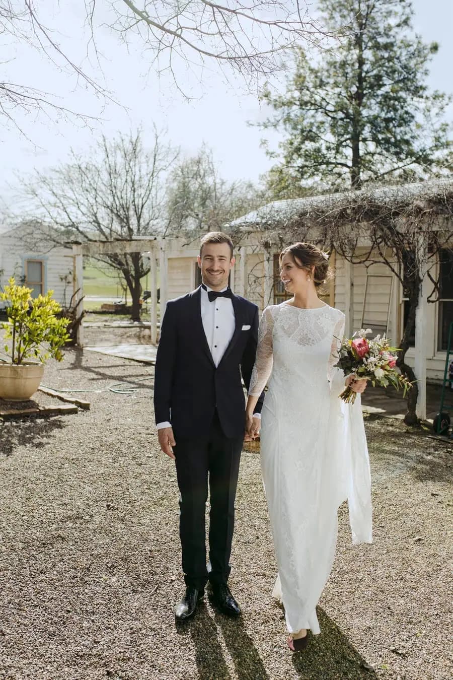 Bride and groom holding hands outside the cottage