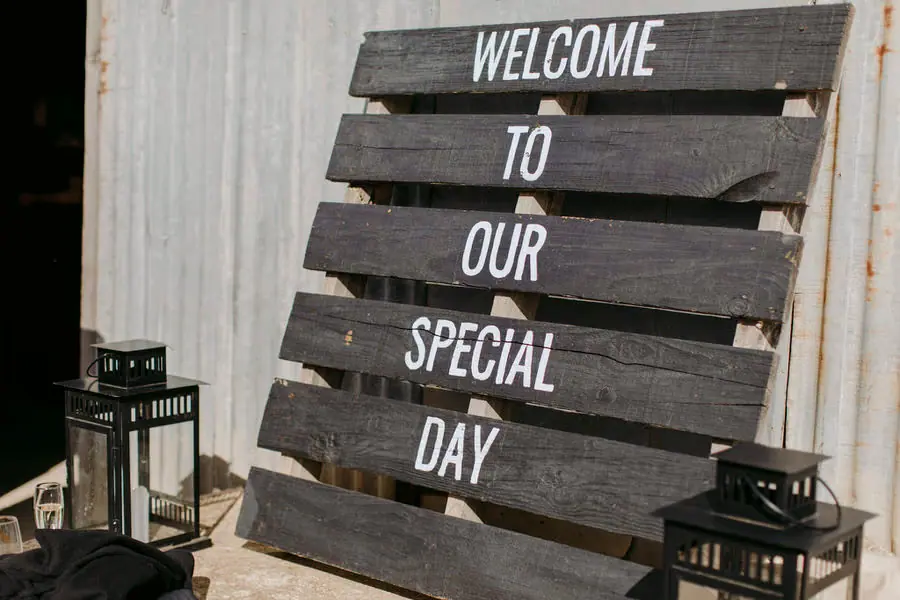 Wooden welcome sign beside black lanterns at the reception entrance