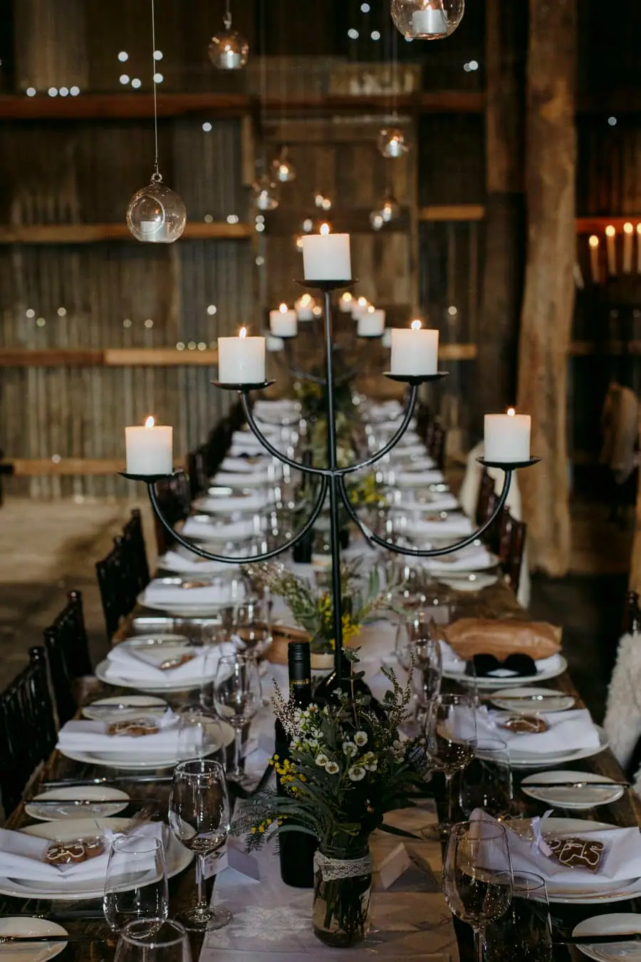 View along a reception table lined with tall black candle holders