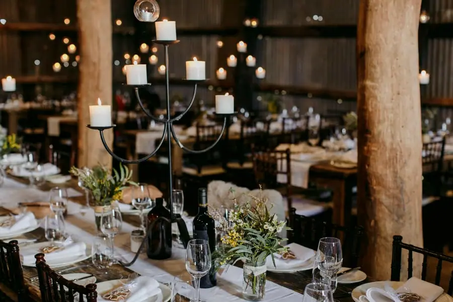 Candles, greenery and place settings beside a timber post at the reception