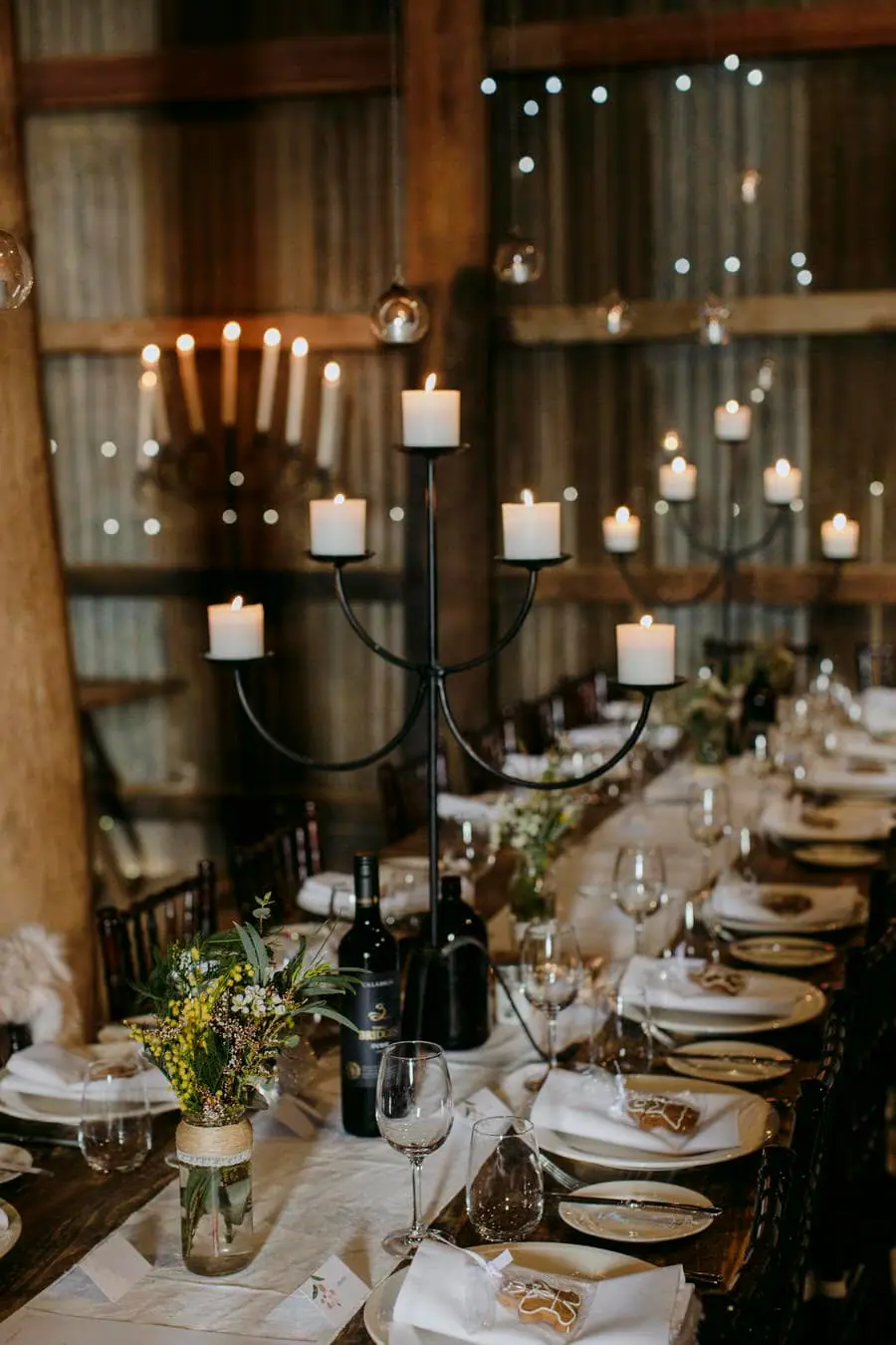 Long reception table with candles, wine glasses and white napkins