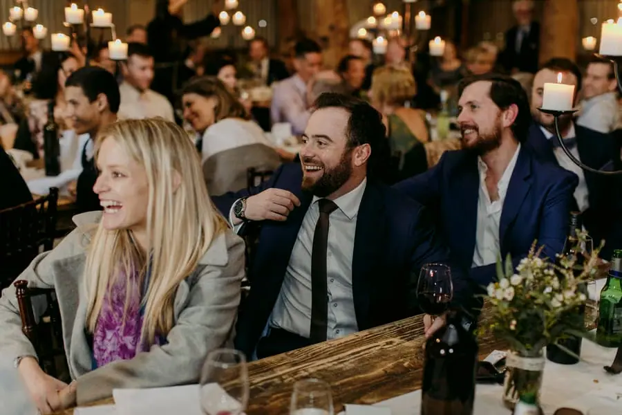 Reception guests laughing around a candlelit table