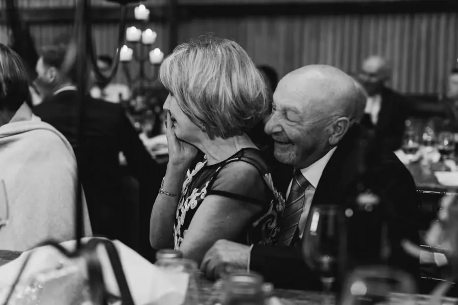 Black-and-white photograph of an older man leaning in to embrace a woman at the reception