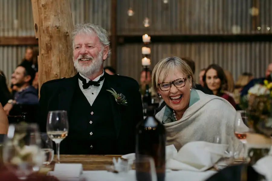 Older couple laughing together at a candlelit reception table