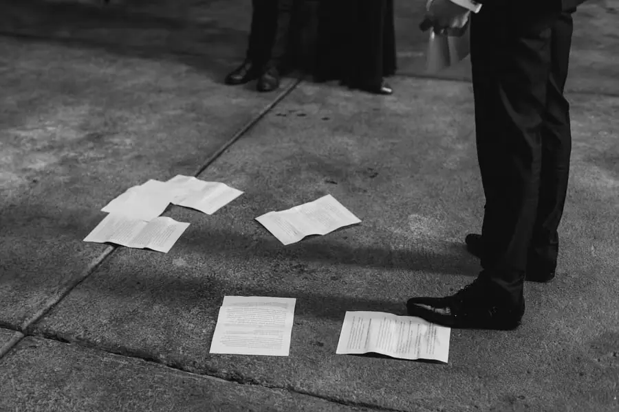 Black-and-white photograph of loose speech pages scattered beside a speaker’s feet
