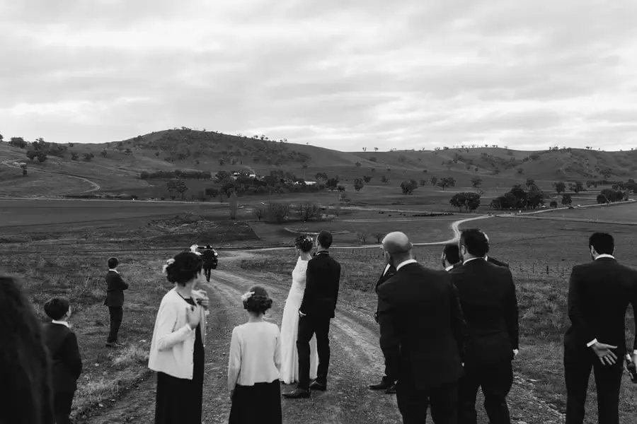 Black-and-white photograph of the wedding party looking over rolling hills