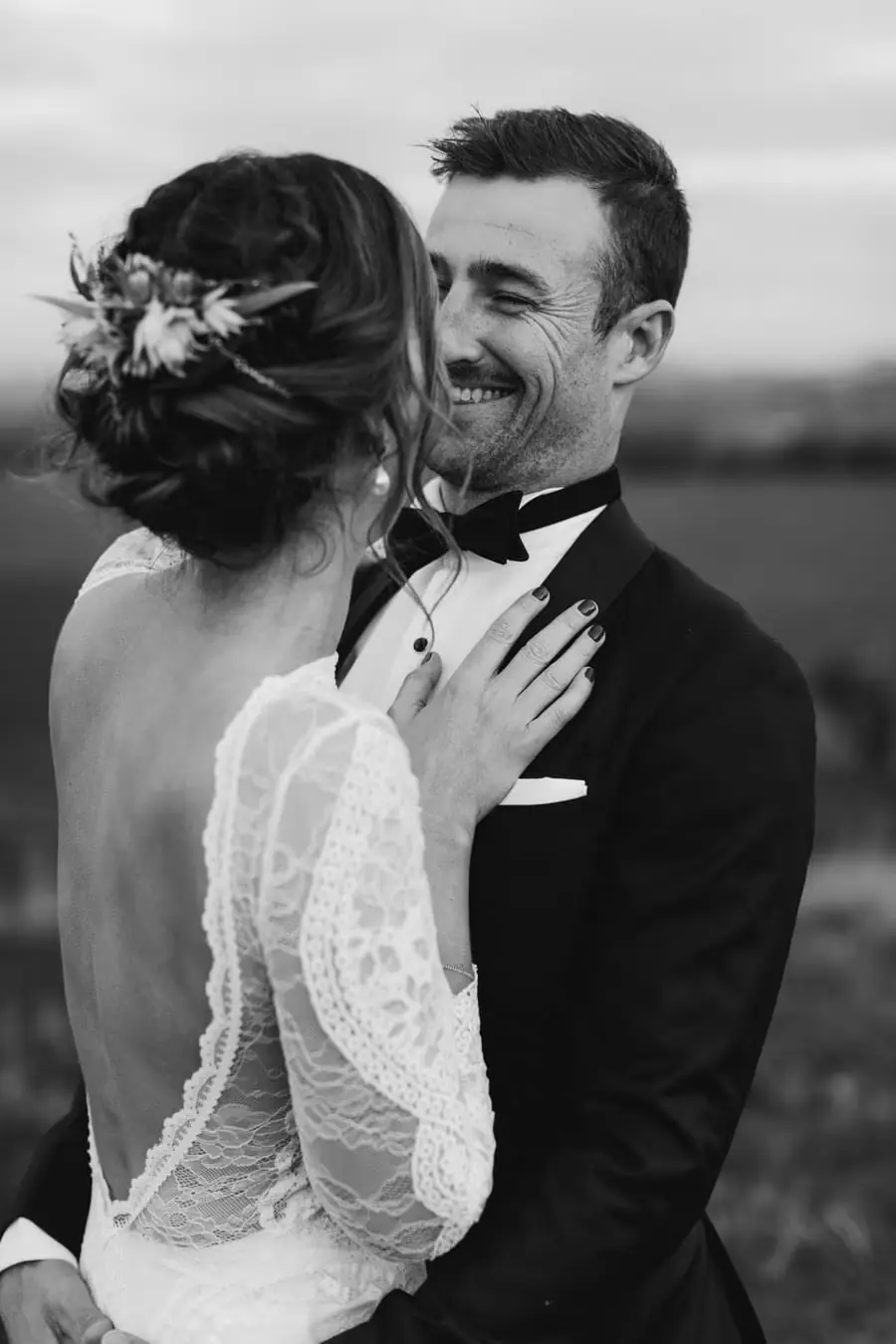 Black-and-white photograph of the couple embracing as the groom laughs