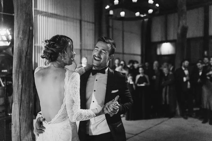 Black-and-white photograph of the bride and groom laughing during their first dance