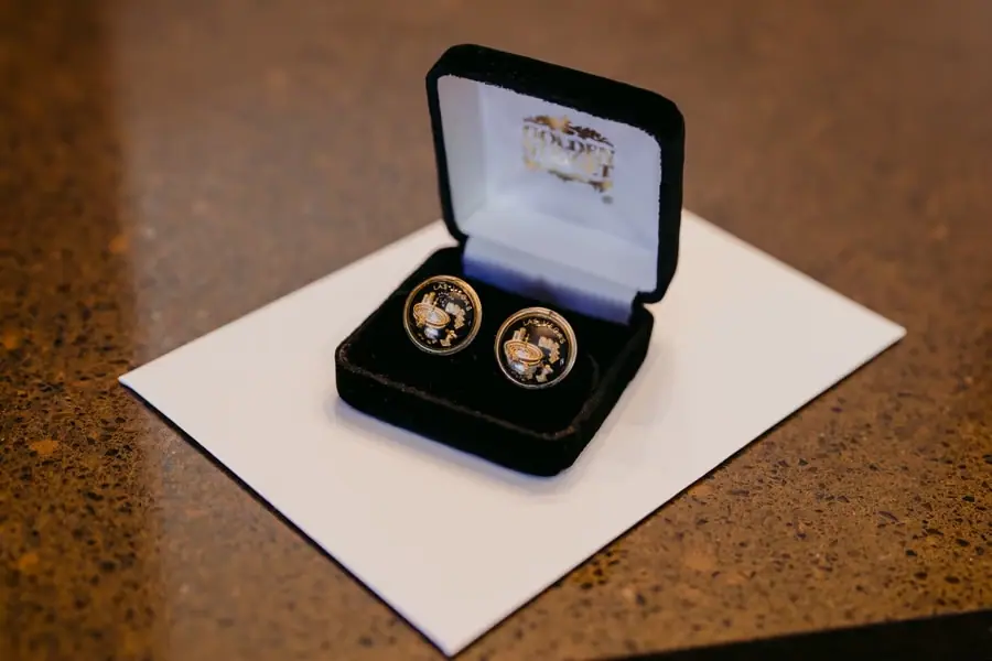 Decorative round cufflinks displayed in an open black presentation box
