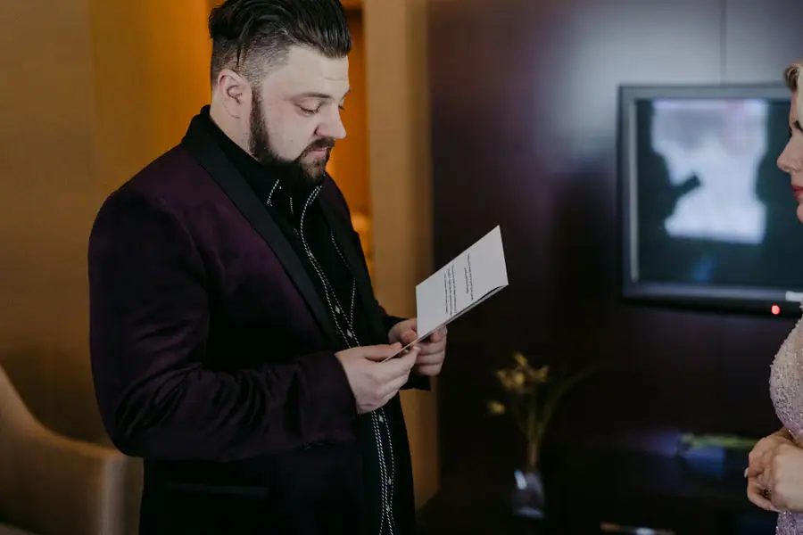 Groom reading a card while standing in a hotel room