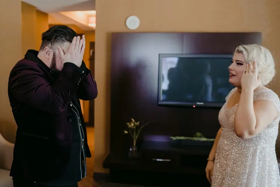 Bride and groom wiping their faces while standing together in a hotel room