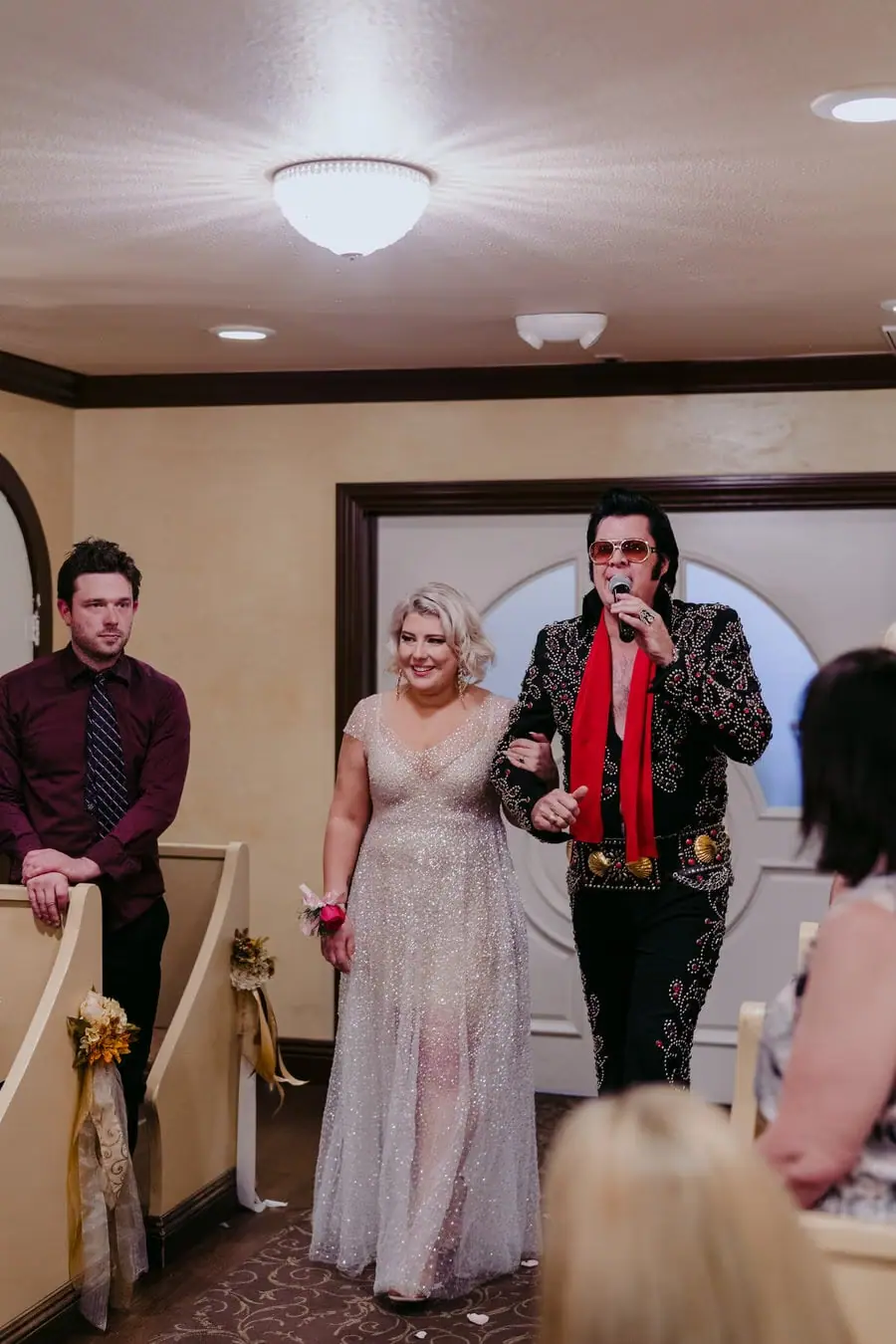 Bride standing beside an Elvis impersonator holding a microphone in the chapel