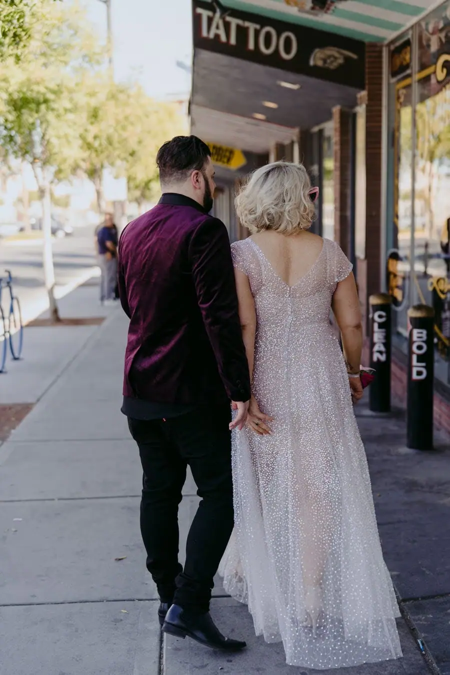 Bride and groom approaching a tattoo shop hand in hand