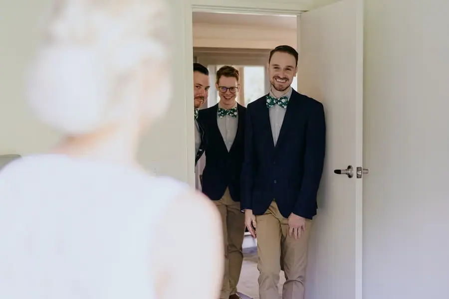 Friends smiling from a doorway as a bride stands before them