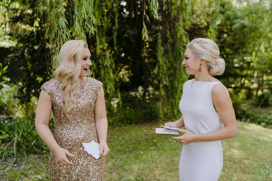 Two brides turning toward one another and smiling in a garden