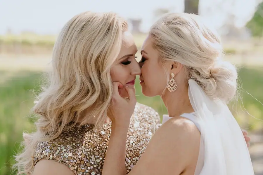 Close portrait of two brides touching foreheads and smiling