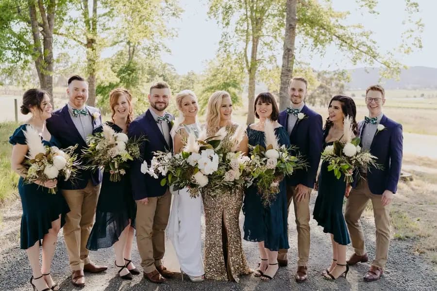 Wedding party standing together with white bouquets on a shaded driveway
