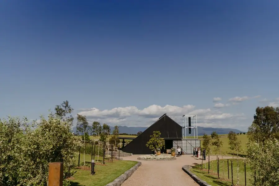 Dark timber ceremony building beside a path and newly planted trees
