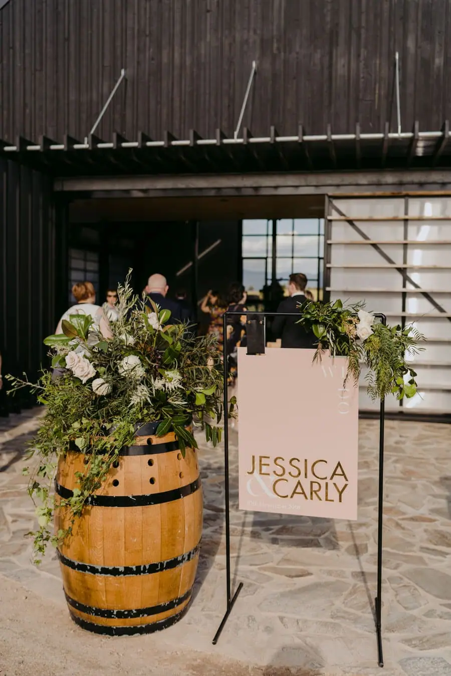 Flower-decorated wine barrel beside a wedding welcome sign