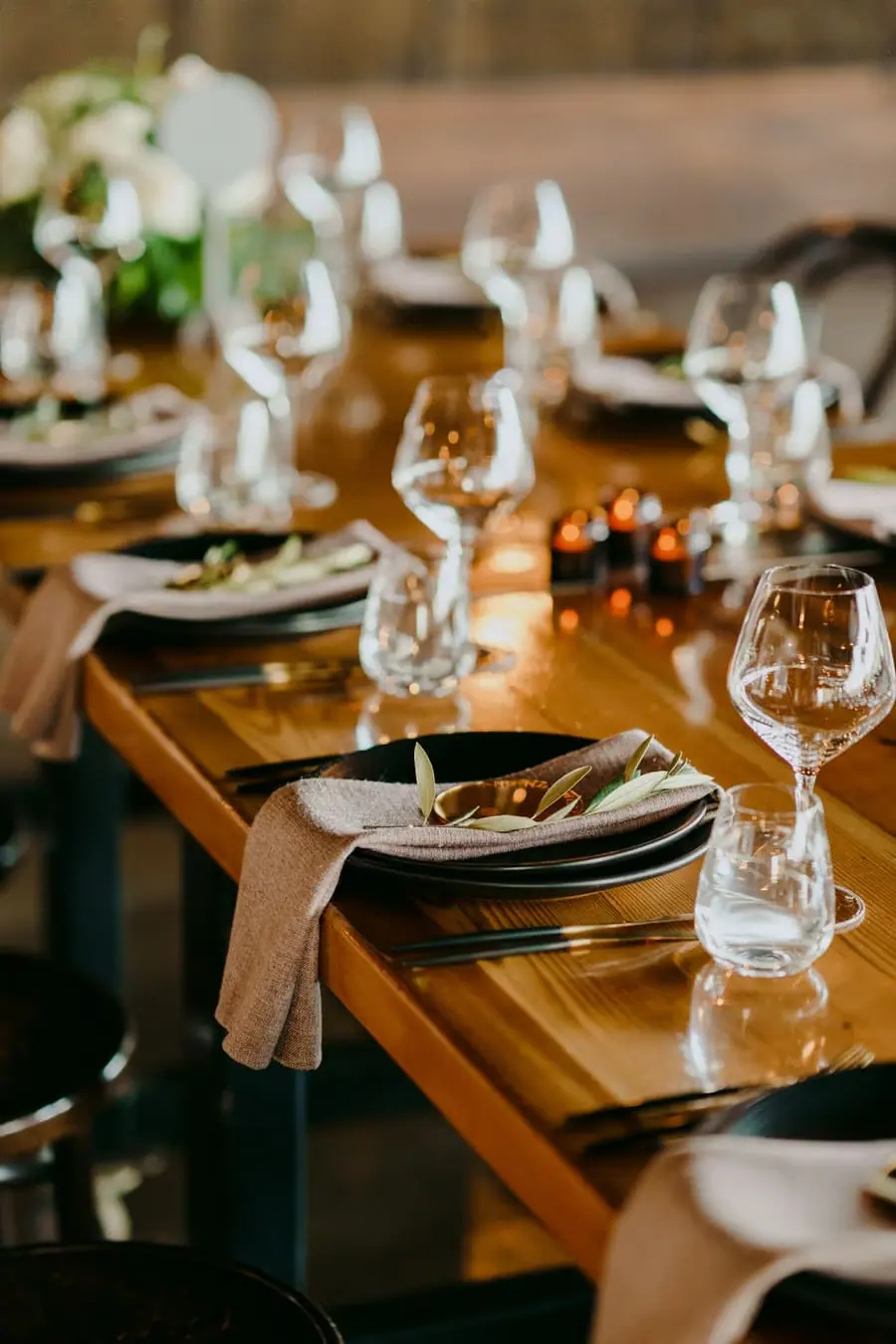 Wine glasses and plates arranged along a wooden reception table