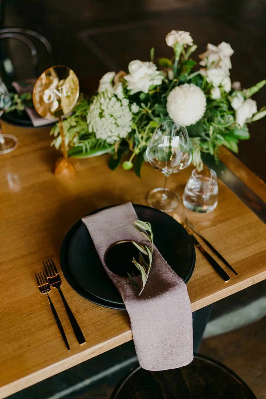Dark plate, pale napkin and floral centrepiece on a reception table