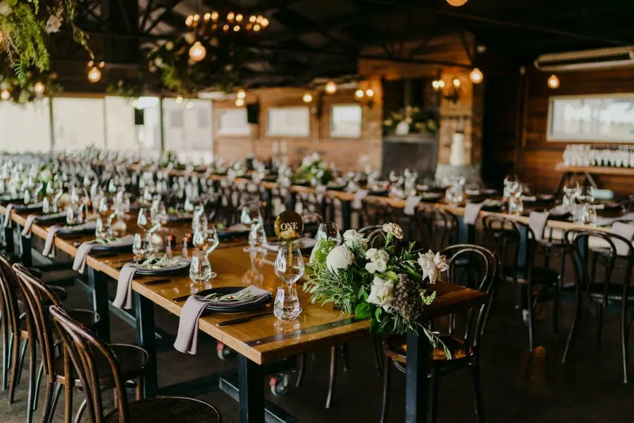 Reception tables set with glassware, black chairs and floral arrangements