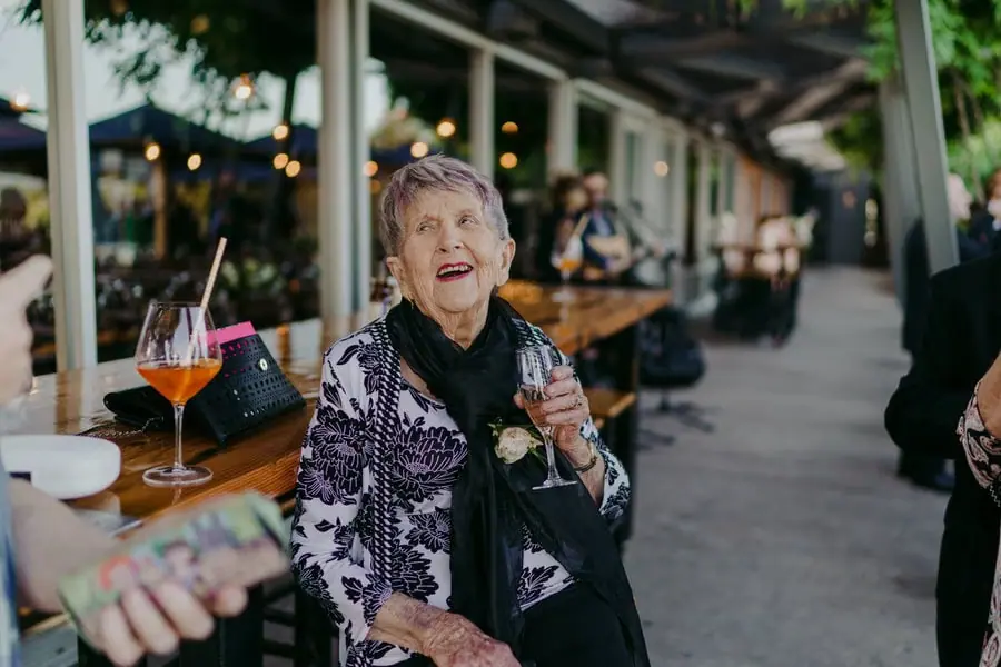Older guest seated beside a table with a wine glass