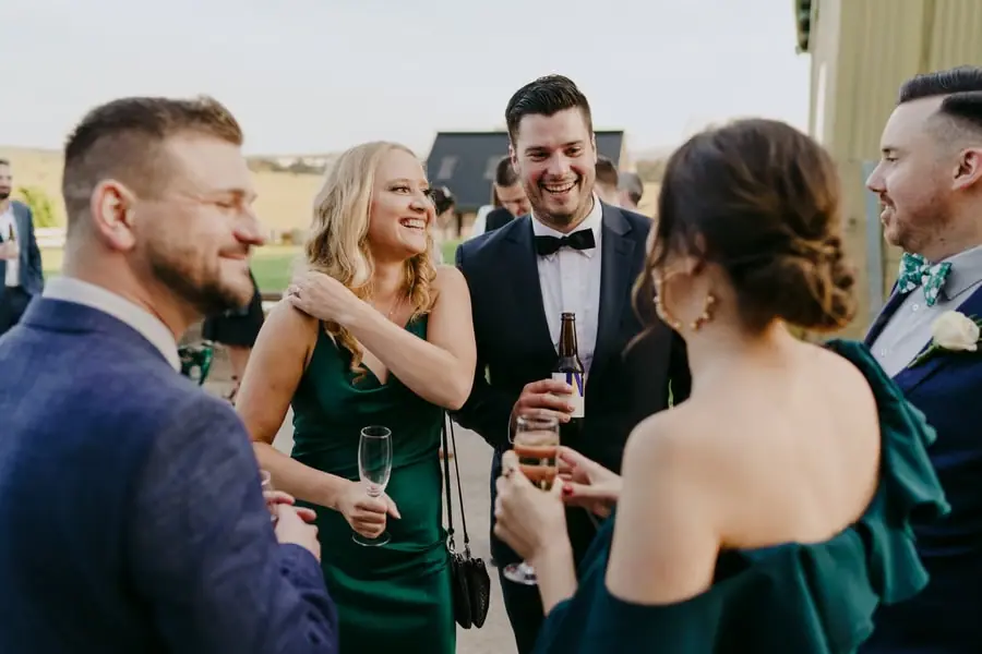 Wedding guests smiling and chatting with drinks outdoors