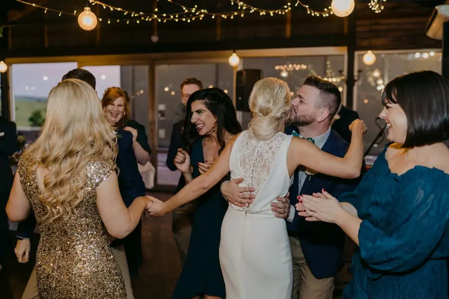 Two brides greeting and embracing guests inside the reception room
