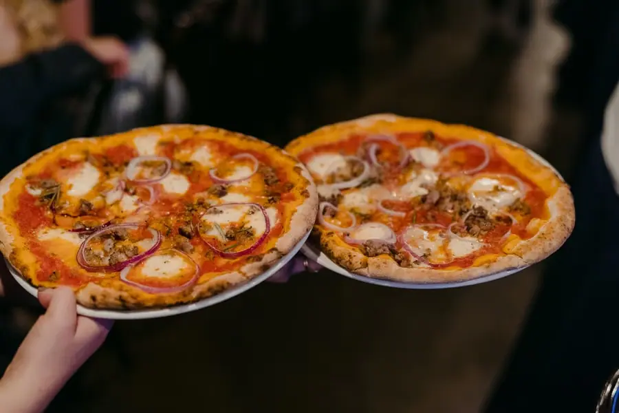 Two pizzas being carried into the reception room
