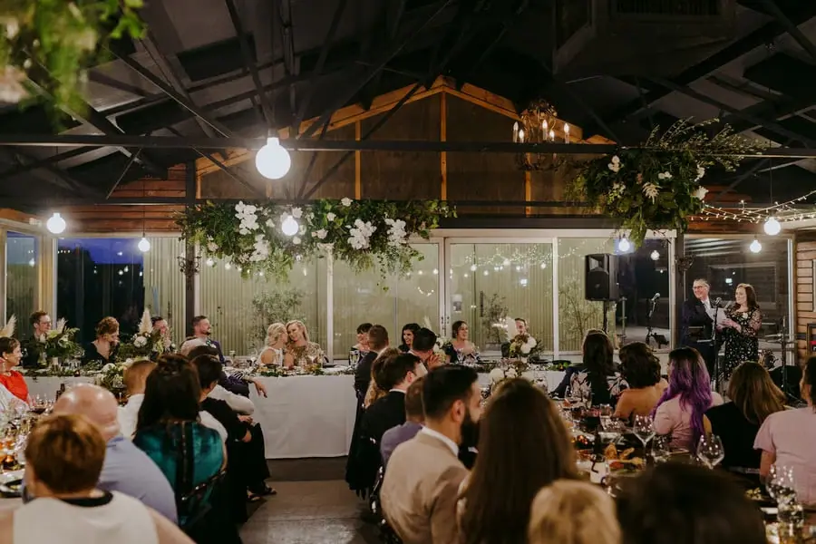 Wide view of guests dining beneath exposed beams and hanging flowers