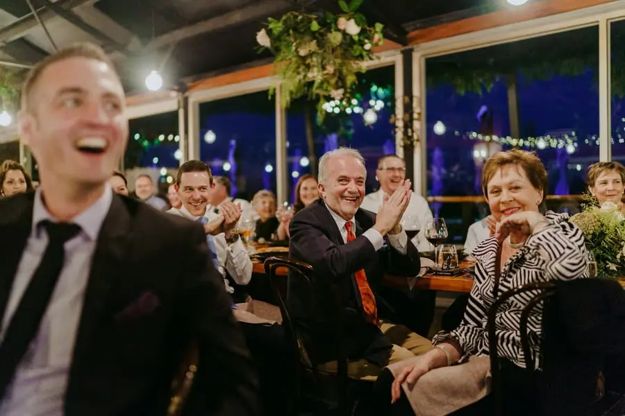 Guests laughing and applauding around the reception tables