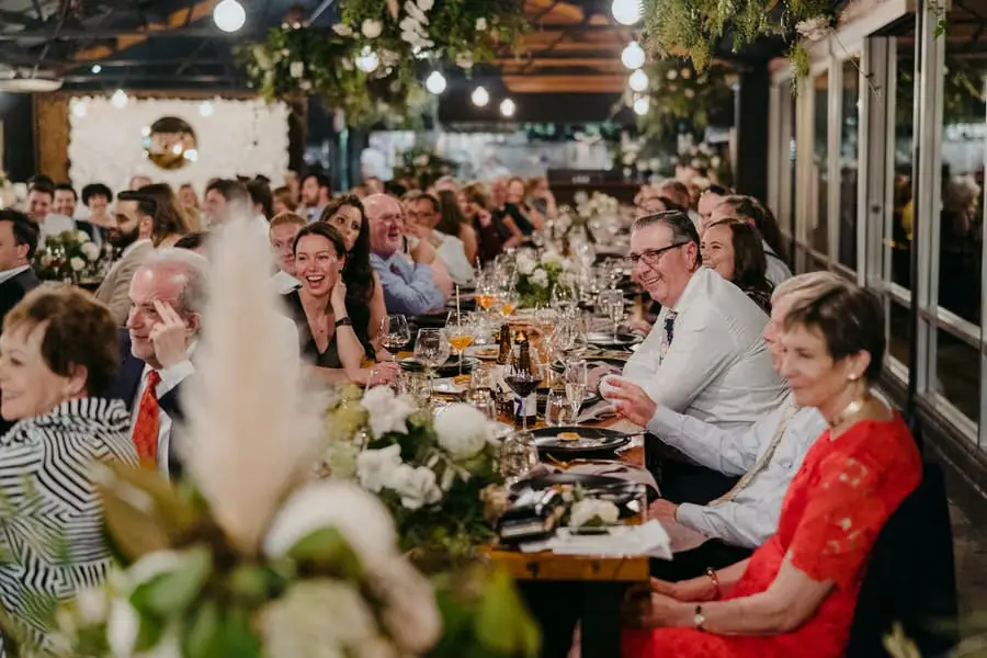 Wedding guests applauding along a long reception table