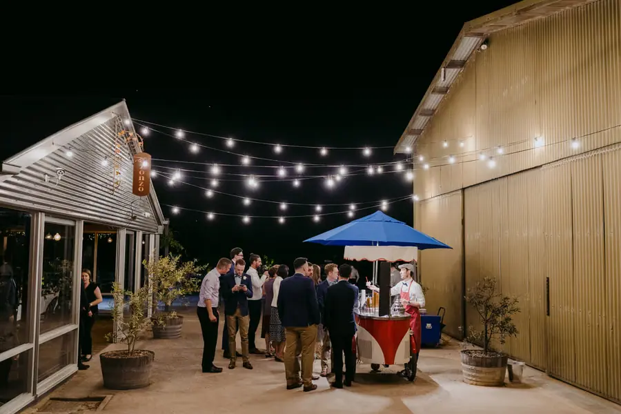 Guests gathering around an outdoor gelato cart beneath festoon lights