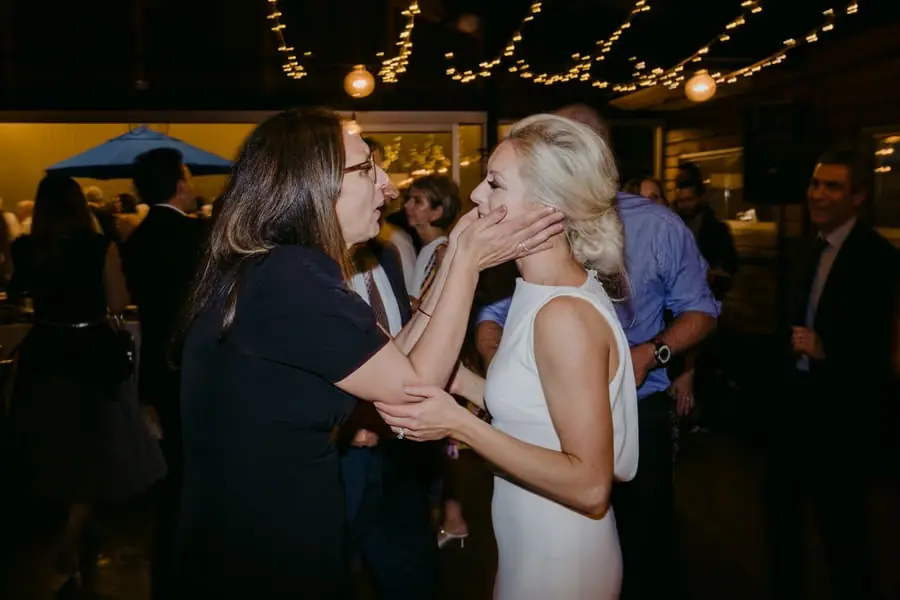 Guest touching the smiling bride's cheek amid the reception crowd
