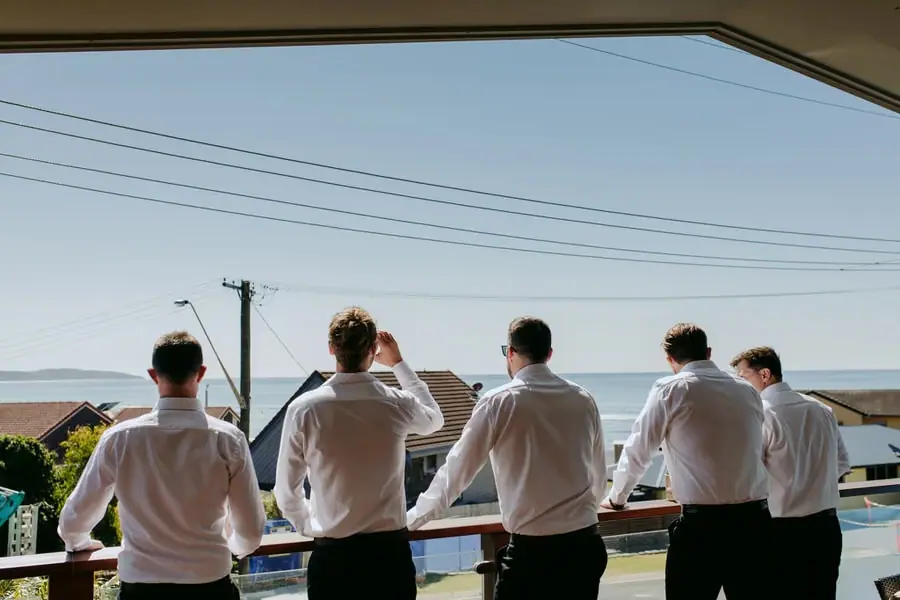 Five men looking out from a balcony toward the sea