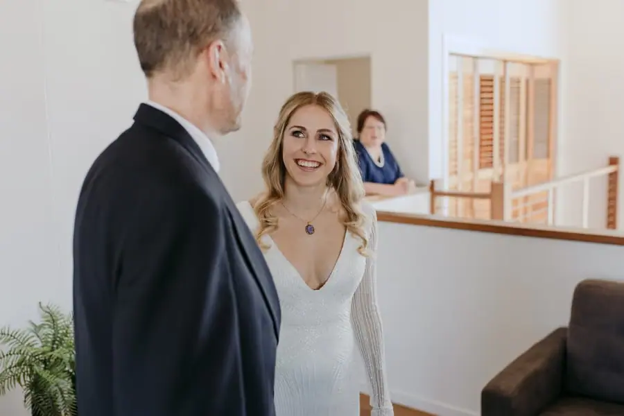 Bride smiling at a man in a dark suit indoors