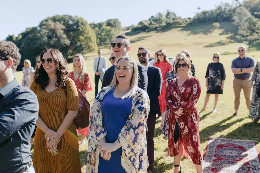Wedding guests laughing while standing on a sunny lawn