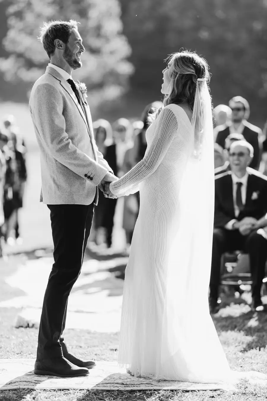 Black-and-white photograph of the bride and groom holding hands during the ceremony