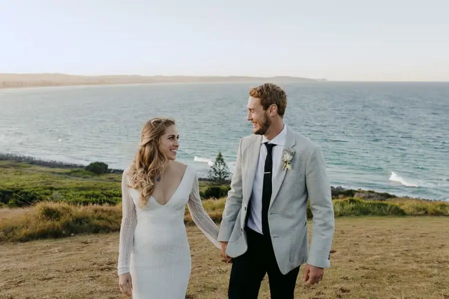 Bride and groom holding hands on a headland above the sea