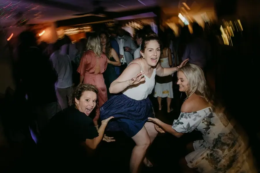 Guests dancing together beneath warm reception lighting