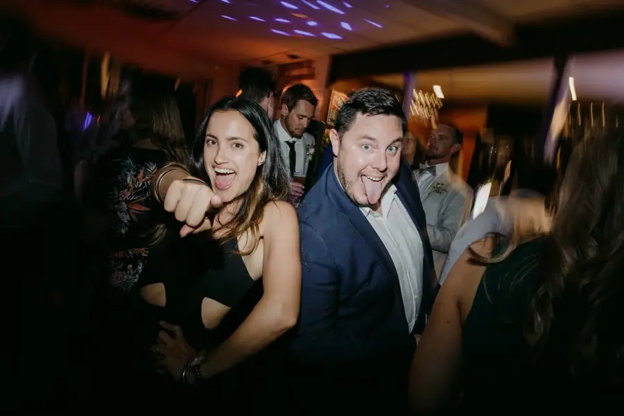 Two guests pointing and smiling toward the camera on the dance floor