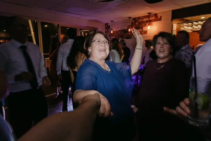 Guests laughing and dancing together beneath coloured lights